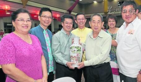 陈祈福（左3）赠送由海鸥赞助的巨型巴戟酒给全场最老的男宝宝姚克姜（104岁，右二）。左起为姚克姜女儿姚亚美、陈金泉及郑今智，右一为姚克姜儿子姚金吉。