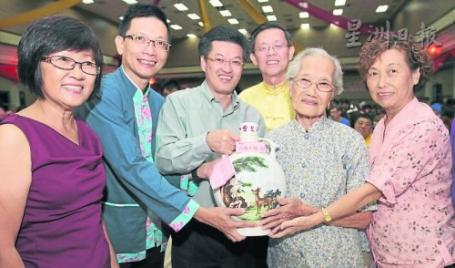 陈金泉（左二起）、陈祈福及郑今智联合赠送由海鸥赞助巨型灵芝酒给全场最老的女宝宝麦亚群（110岁）。右一与左一分别为麦亚群女儿黄亚珍与媳妇郑雅英。