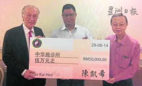 著名企业家兼马华医药总会总会长陈凯希（左）移交5万令吉善款的模拟支票给马来西亚中医师公会，并由中华施诊所60週年筹款千人宴筹委会主席谢奇医师（右）接收，由马来西亚中医师公会会长杨伟雄博士见证。