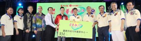 出德隆（左五）和陈金泉（左六）移交模拟支票给重新华小，由江绍荣（右五）和李新雄（右四）接领。左一起是陈君成、李燕霞、谢绍辉及黄绍铭；右一起为朱兴富、何君简和岳忠诚。