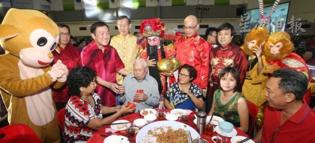 黄家泉（站者左三）满心欢喜为长者送上红包，祝愿他们平安健康。图为全场最年长的老宝宝，即103岁的曾炳苏接领红包。站者左二廖天雄、左四谢绍辉；右三起为黄传易及黄绍铭。